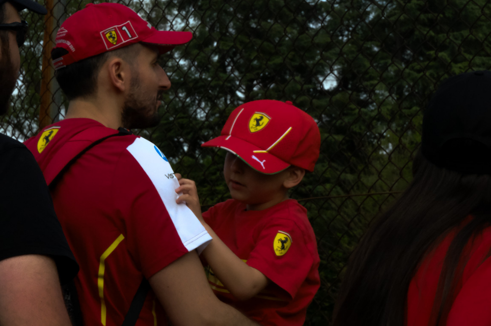 Scatto di Erika De Summa al WEC 2026 di Imola di padre con in braccio il figlio con cappello e maglietta Ferrari